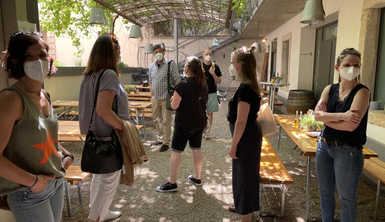 Innenhof mit Bierbankgarnitur davor stehen fünf Frauen und im Hintergrund zwei Männer